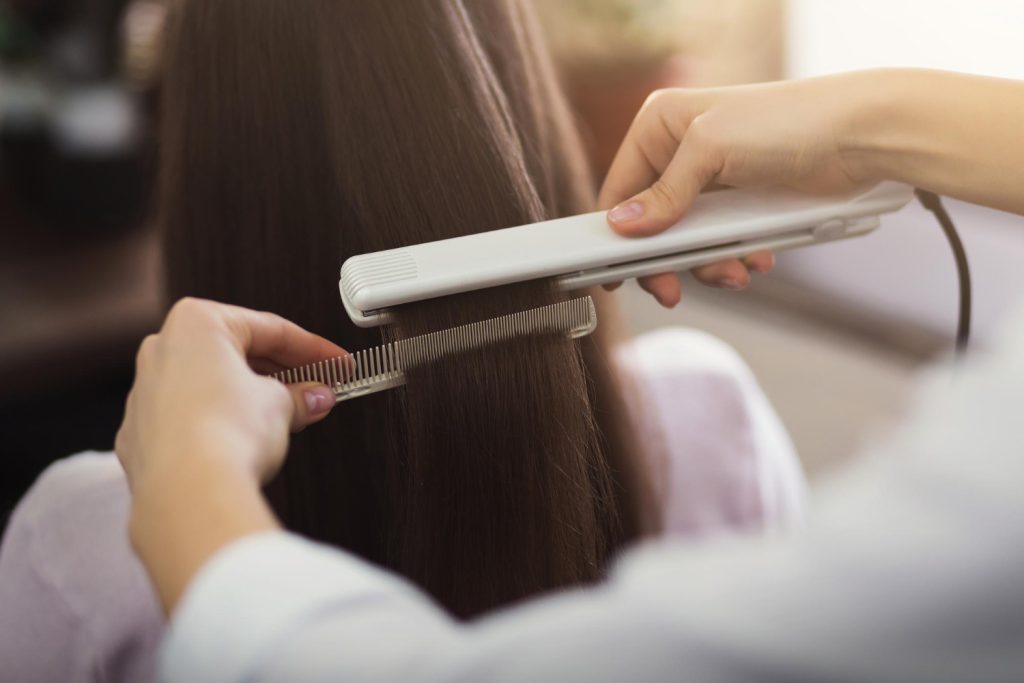 Mulher realiza alisamento que não danifica o cabelo em um salão de beleza.