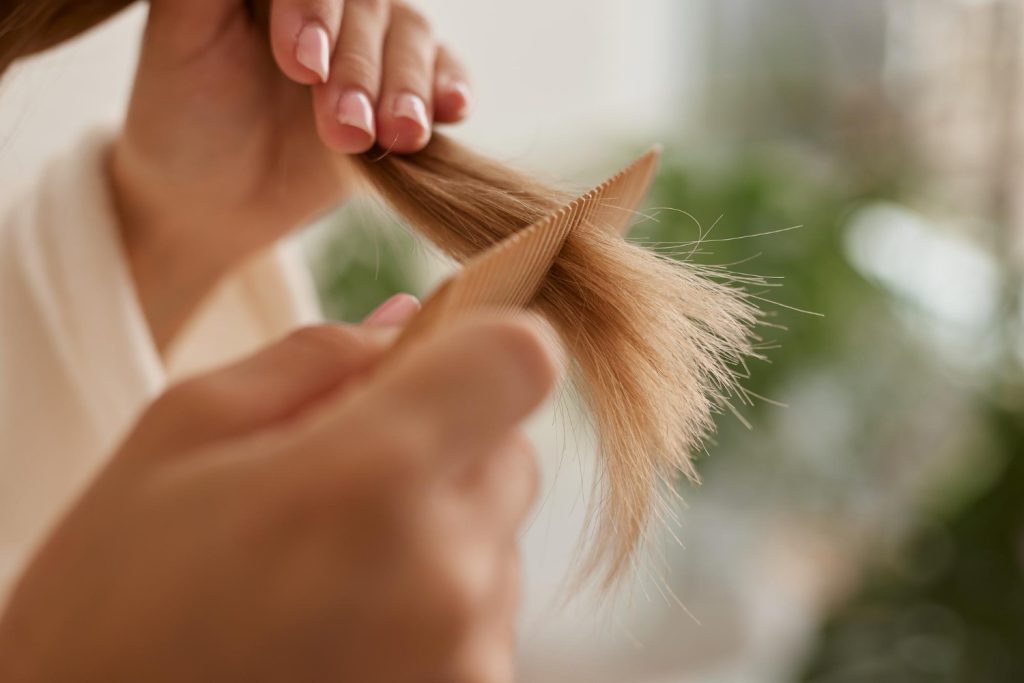 Pessoa cuidando das pontas do cabelo para evitar o frizz, ilustrando a importância da nutrição para controlar pontas duplas e desalinhamento dos fios.
